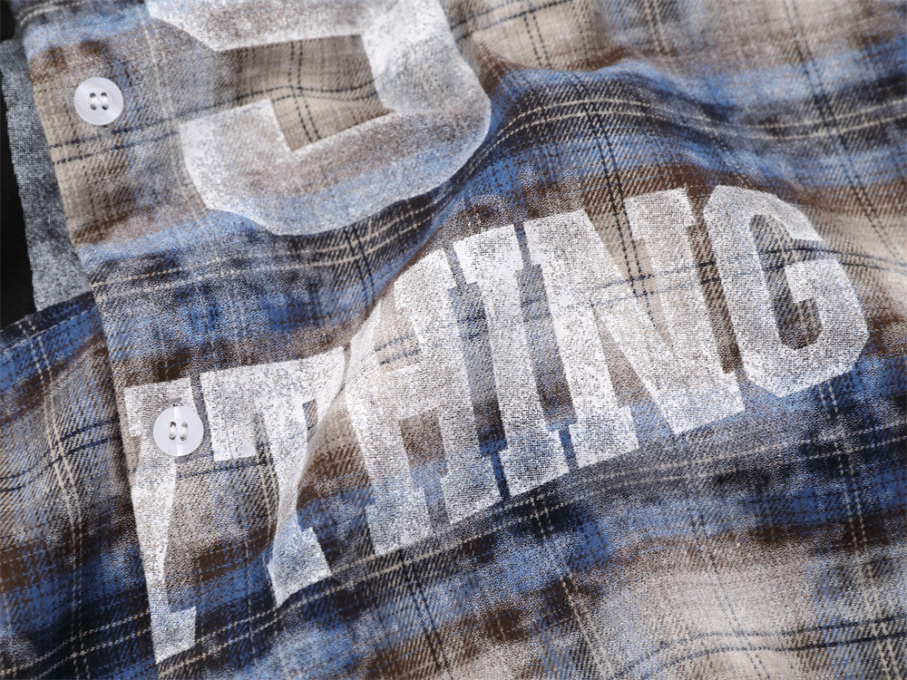 Close-up of bold white lettering on blue plaid shirt front