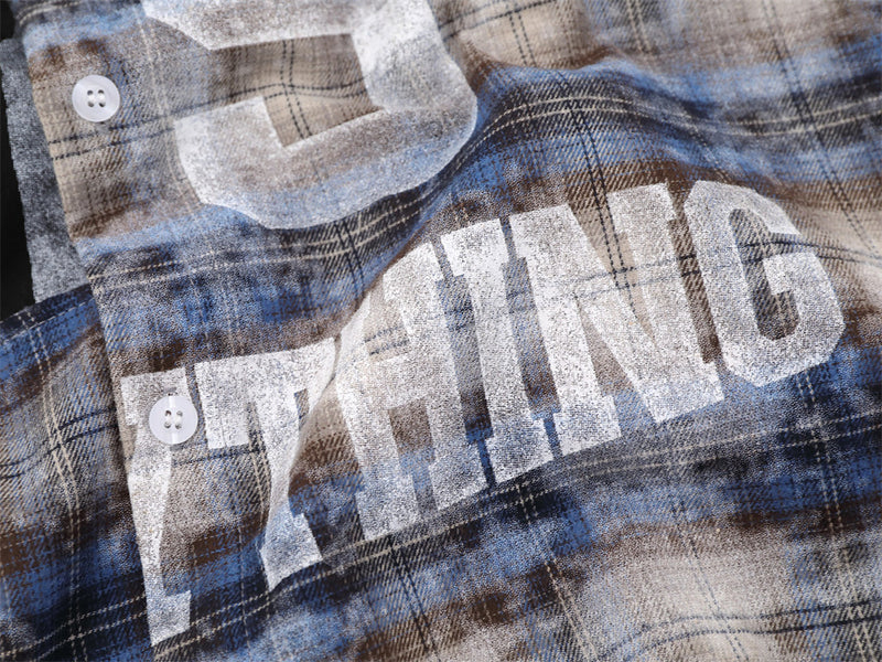 Close-up of bold white lettering on blue plaid shirt front