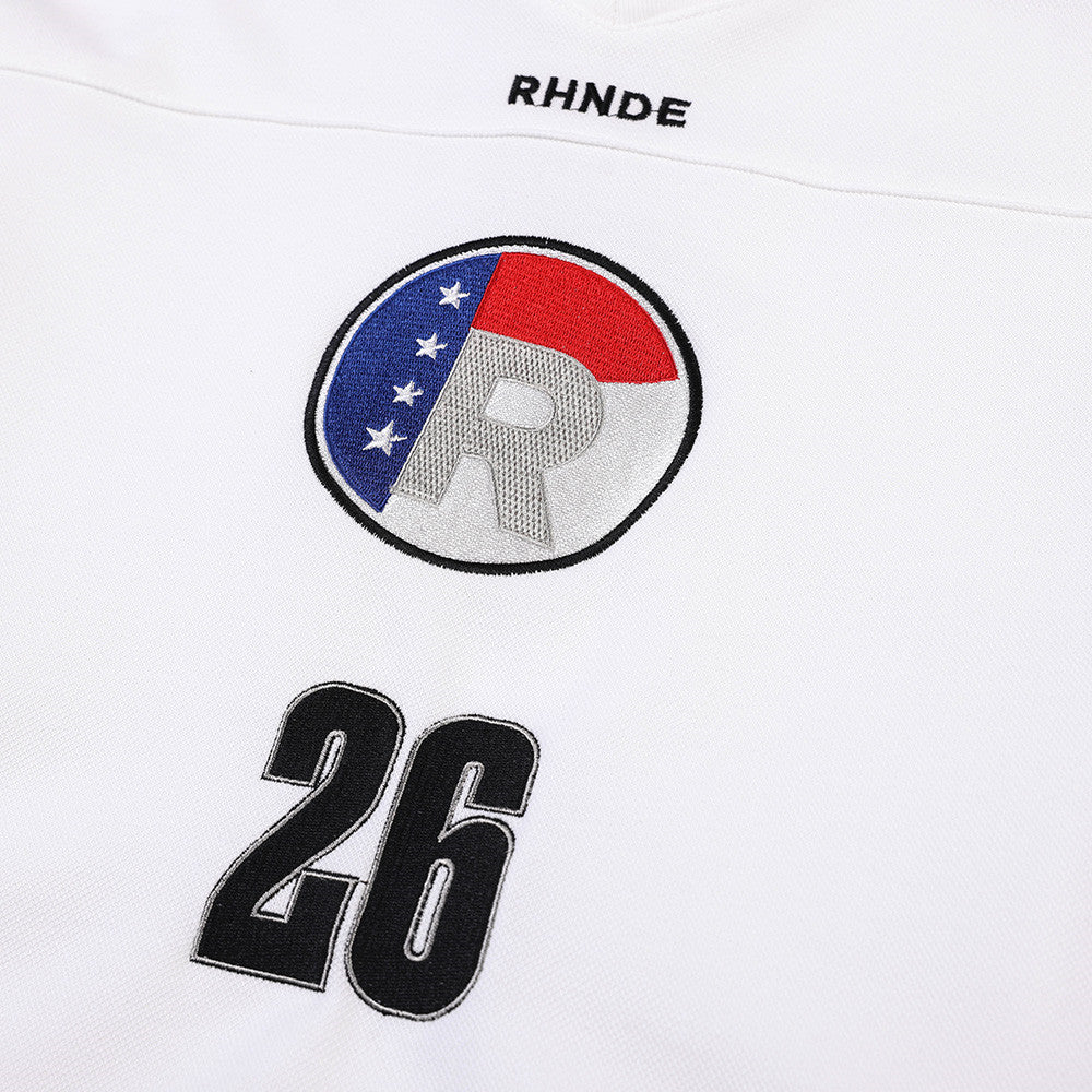 Close-up of chest embroidery on white jersey with circular R logo and number 26