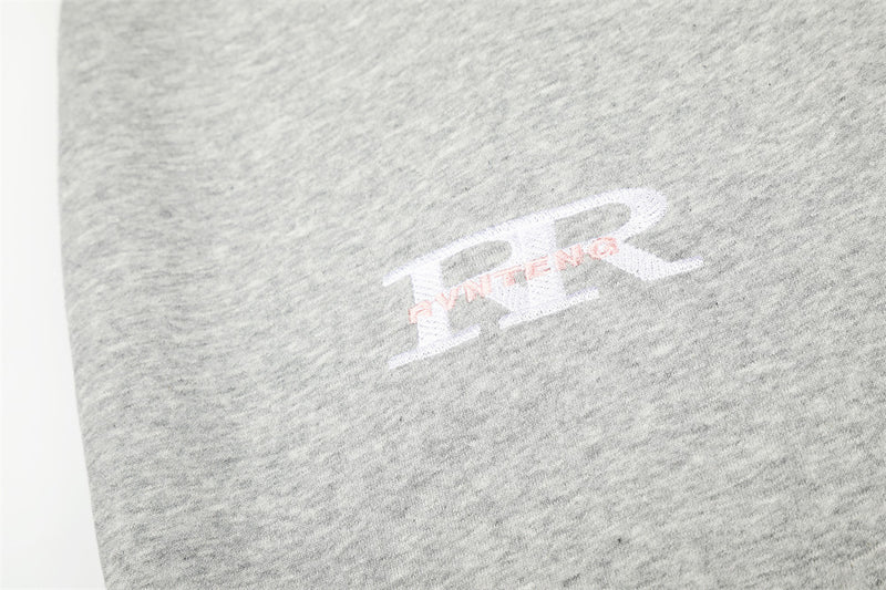 Close-up of white and pink PR-style chest print on heather gray sweatpants