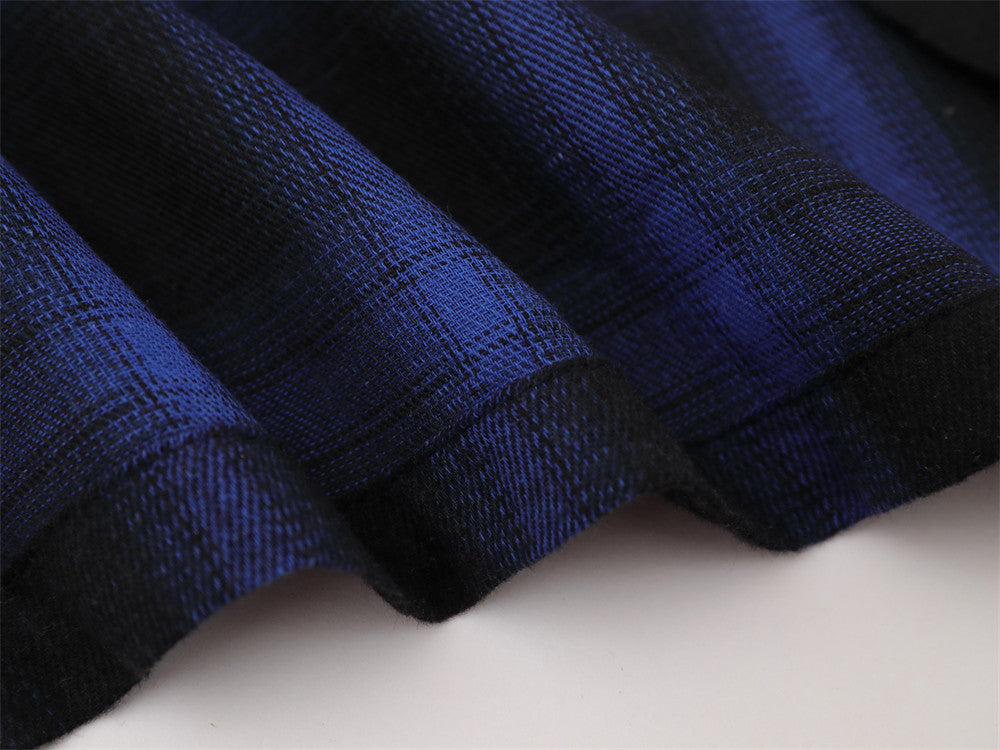 Close-up of blue plaid sleeve hem with black cuff detail