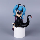 The Hatsune Miku Little Demon Sitting Pose 11cm PVC Figure, featuring light blue twin ponytails and a black outfit with dark purple accents and a large scorpion tail, sits on a white cylinder. This stylish addition to any anime collection is set against a plain gray background.