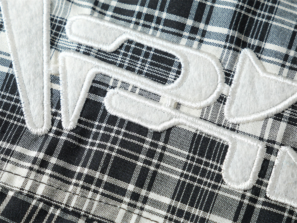 Close-up of white embroidered pocket logo on black plaid shirt