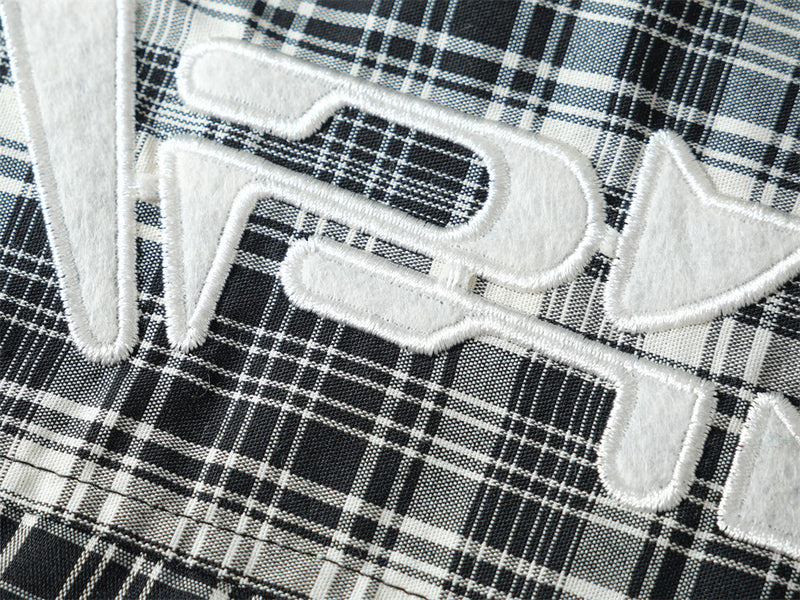 Close-up of white embroidered pocket logo on black plaid shirt