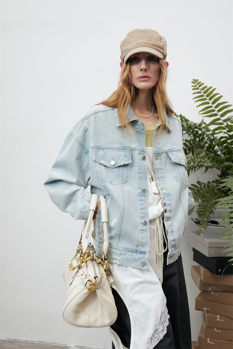 Close model view showing the jacket's light wash denim, chest pockets, buttons, and distressed finish
