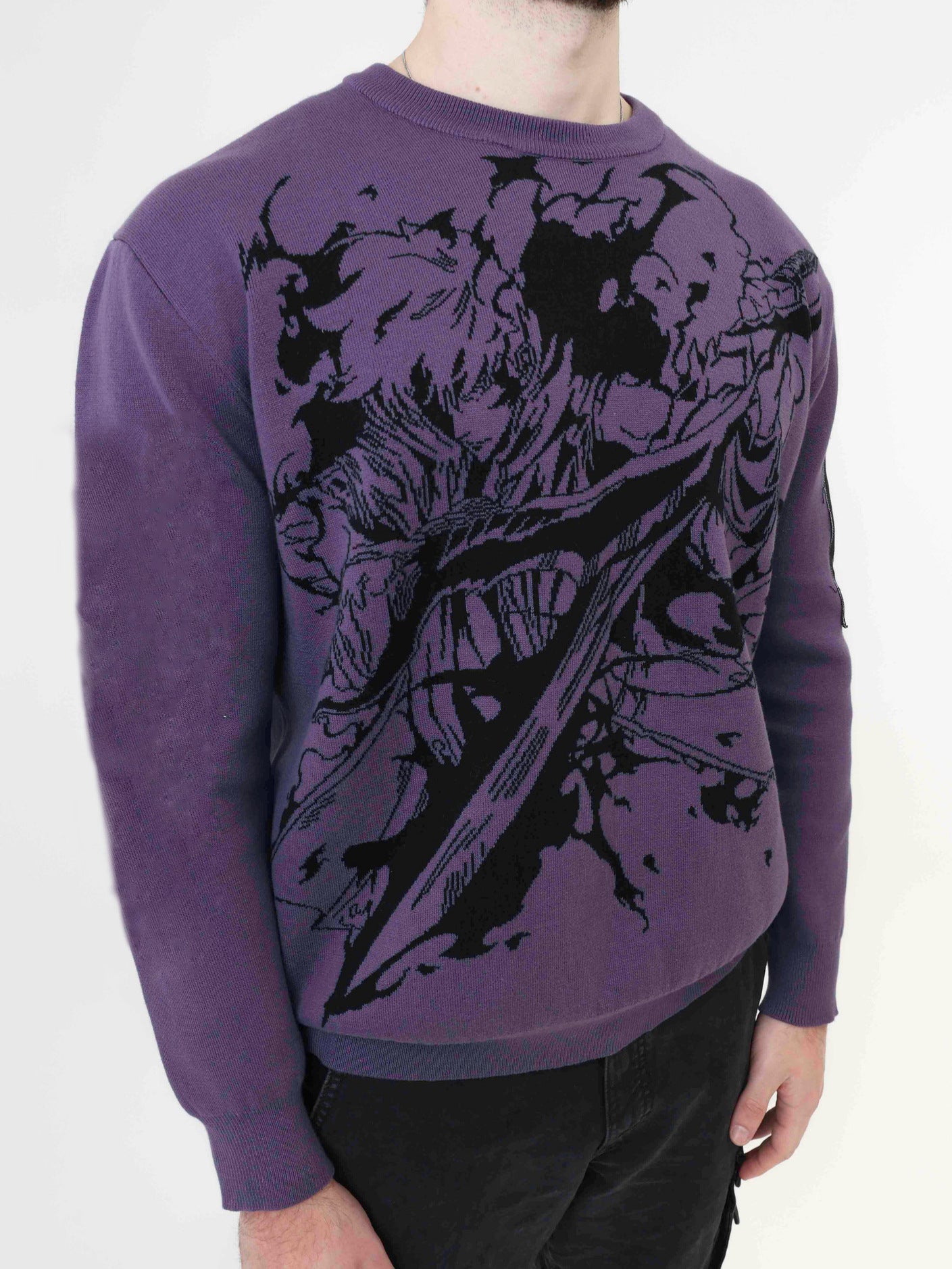 A person wearing the Solo Leveling Premium Knit Sweater featuring a detailed Sung Jinwoo Shadow Monarch jacquard design in purple is paired with black pants, standing against a white background.