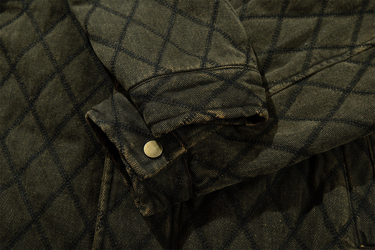 Close-up of a quilted jacket sleeve cuff showing a folded tab and round metal snap