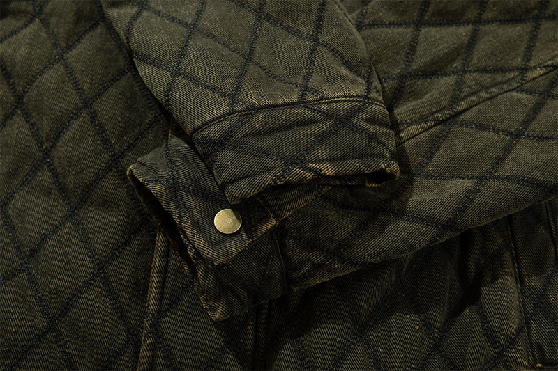 Close-up of a quilted jacket sleeve cuff showing a folded tab and round metal snap