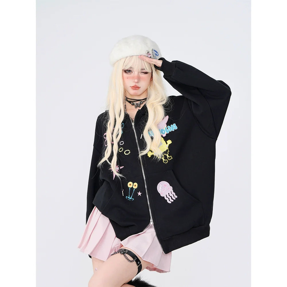 A person with long blonde hair, donning Seakoff's Kelly Kitty Pastel Kawaii Hoodie, an oversized jacket with charming embroidered characters, embodies Japanese streetwear. They adjust their white beret against a plain white background, adding kawaii flair with their stylish choker and pink skirt.