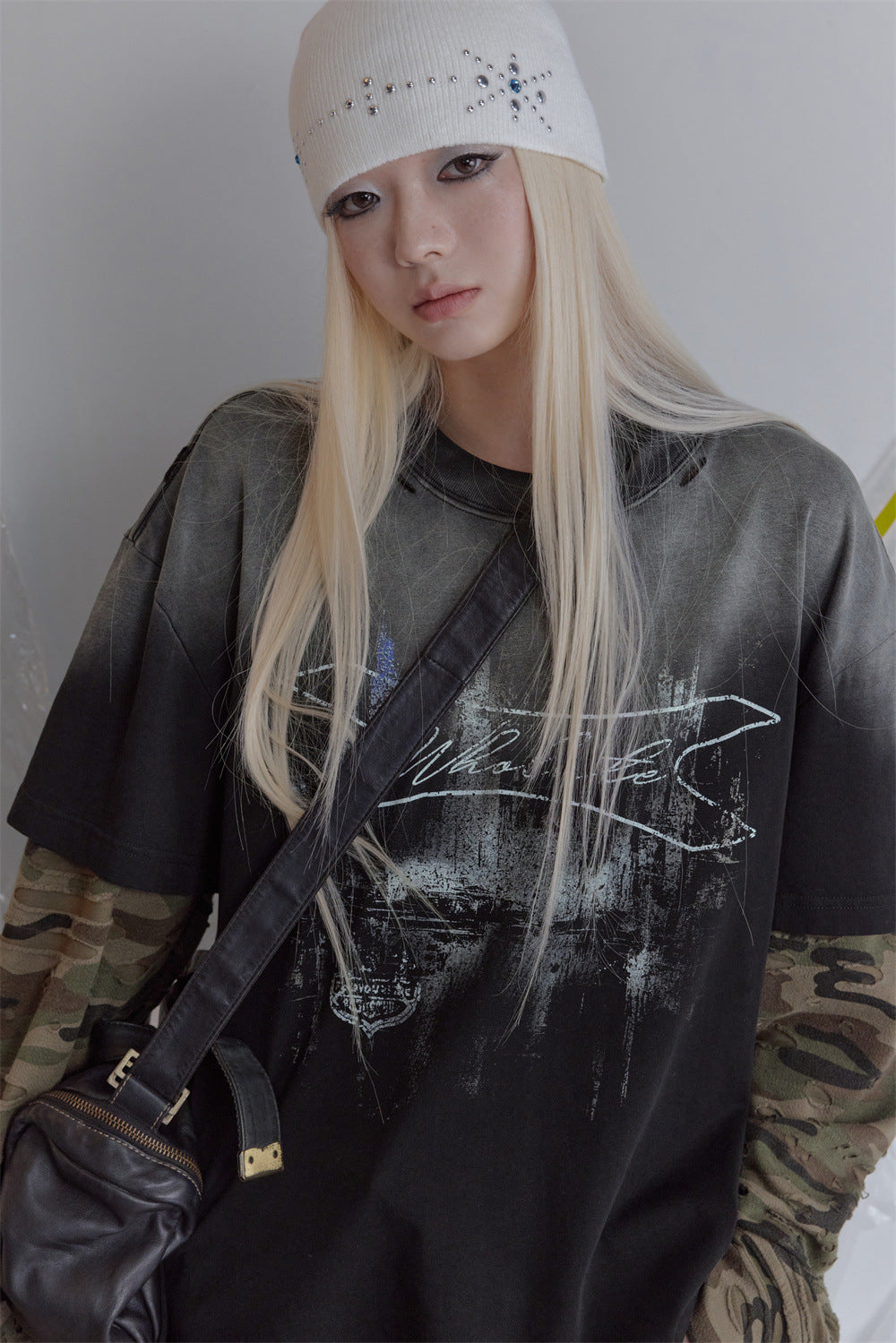 Oversized washed-black faux-layer long sleeve tee with camo splice sleeves and distressed grunge chest graphic