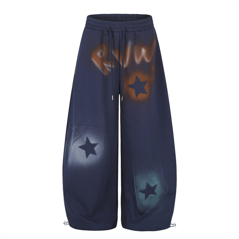 Men's oversized wide leg sweatpants with spray-dye graffiti star print in navy, front view