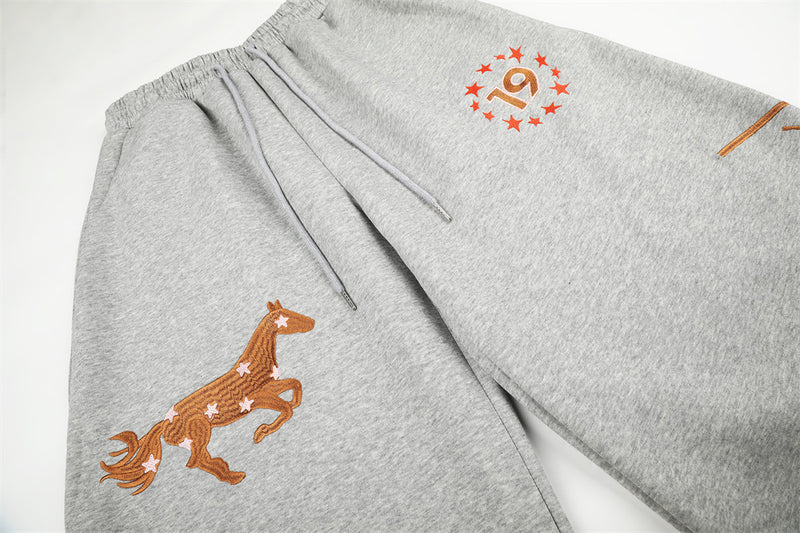 Top view of gray wide-leg sweatpants with horse embroidery, star 19 graphic, and drawstrings