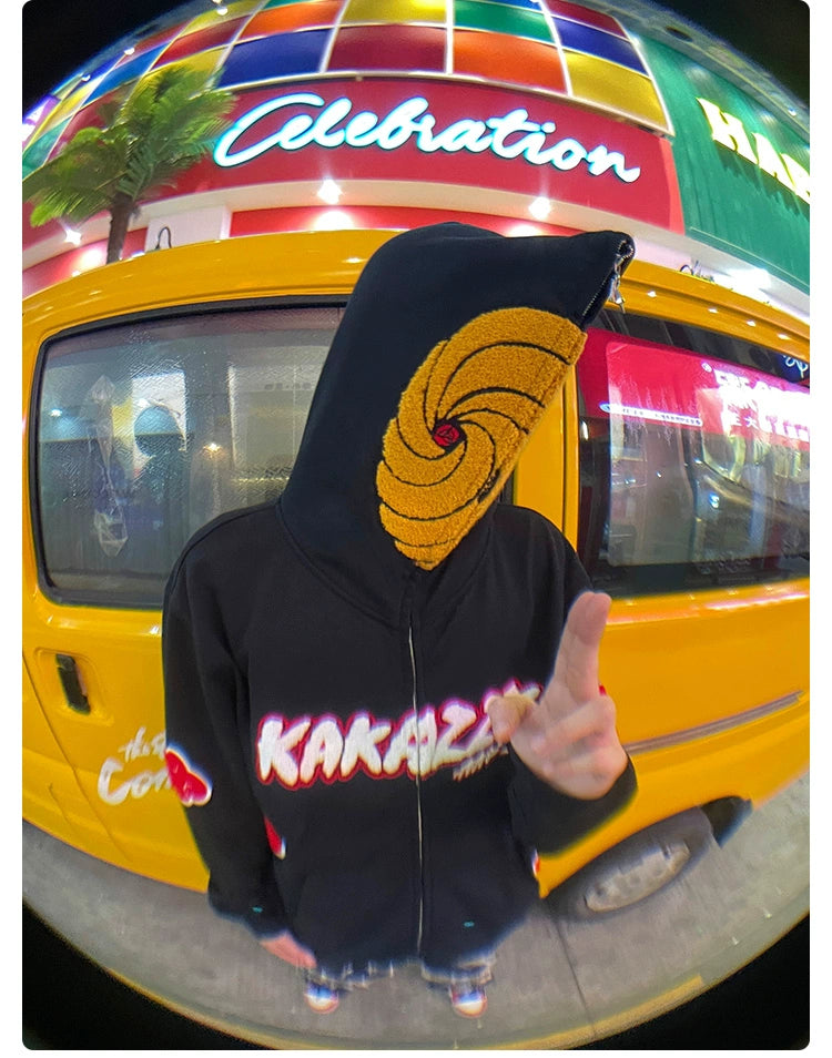 Wearing a Seakoff Uchiha Obito-Inspired Hoodie with an Akatsuki Cloud Design and Spiral Mask, a person stands before a yellow van. Behind them, &quot;Celebration&quot; adorns a colorful building. A striking fisheye lens captures this scene, enticing Naruto fans with its artistic blend.