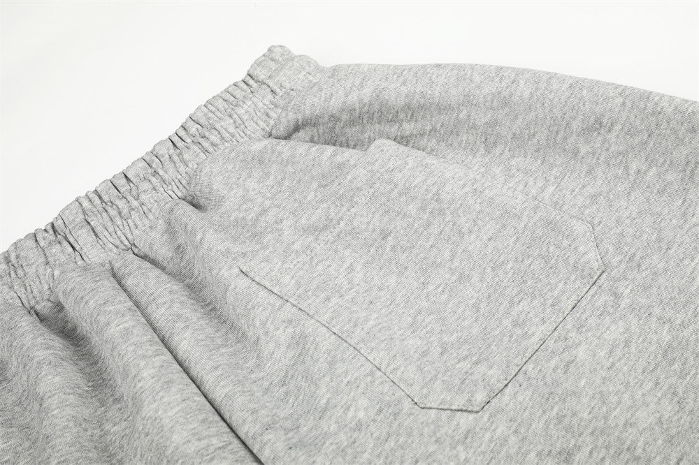 Close-up of gray sweatpants back pocket stitching and waistband gathers