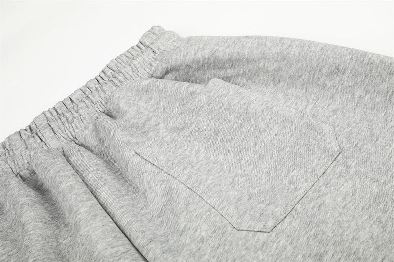 Close-up of gray sweatpants back pocket stitching and waistband gathers