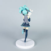 This 21cm PVC figure of Hatsune Miku features her iconic aqua blue hair in a side ponytail and a black and teal outfit. The anime collectible is posed from the back, balancing gracefully on one leg on a circular white base, holding Cinnamoroll.