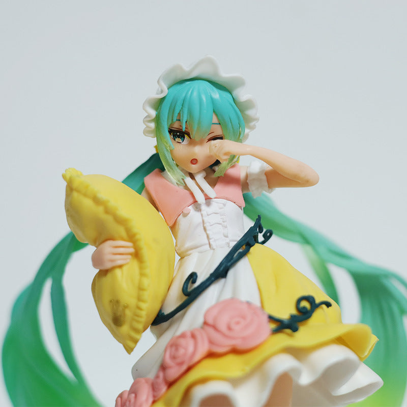 The Fairy Tale Sleeping Beauty Hatsune Miku 19cm PVC Figure, wearing a white bonnet, pink and white dress, and holding a yellow pillow with flowers adorning her outfit, captures the essence of a charming anime character with long green hair and a sleepy expression that Vocaloid fans will love.