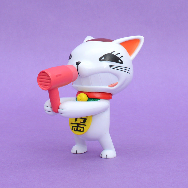 The Dandadan Lucky Cat PVC Figure features a 9.5 cm small, white cartoon cat with dark eye markings and a smiling expression, wearing a red collar with a yellow bell. It holds a pink toy hairdryer in its paws, standing on a purple background in kawaii style.