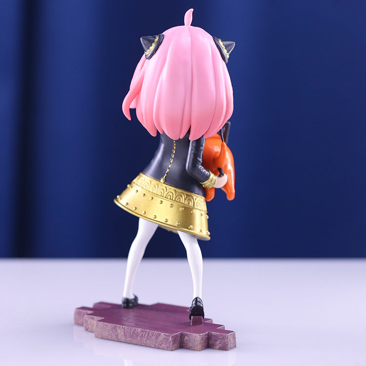 The Anya Forger Chainsaw Cosplay Figure, a Spy × Family 18CM PVC collectible, showcases a pink-haired character with cat ears in a dark jacket and yellow skirt, holding an orange object. It stands on a purple base with a blue backdrop, facing away from the viewer.