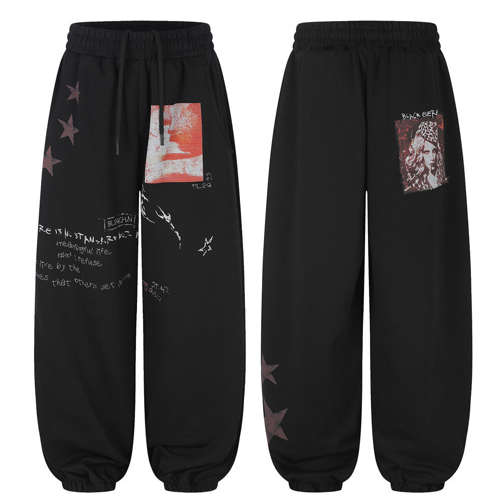 Men's black wide-leg sweatpants with star print, graphic photo patch, and handwritten slogan lettering, front and back view
