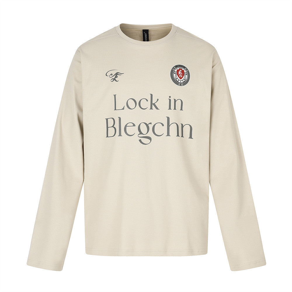 Beige long sleeve crew neck tee, flat lay front view with chest graphic and logo patch