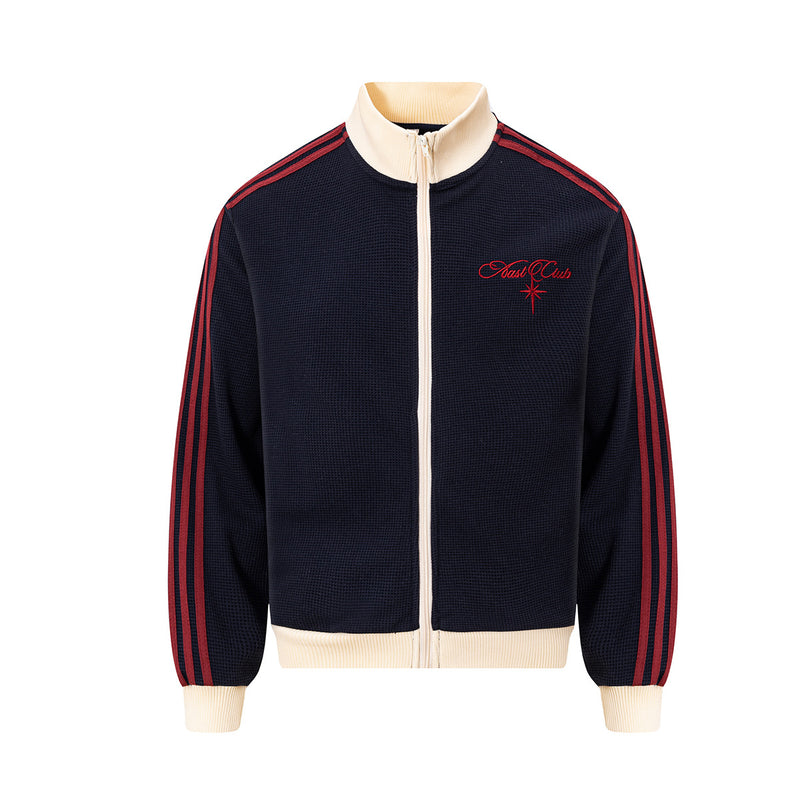 Veste de survêtement Nast Club en maille gaufrée bleu marine, col contrastant crème, manches à trois bandes rouges et logo brodé sur la...