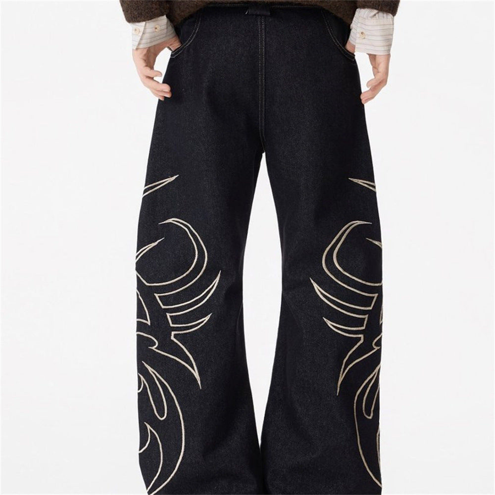 Black baggy wide-leg jeans with cream tribal flame embroidery on both legs, contrast topstitching, streetwear style