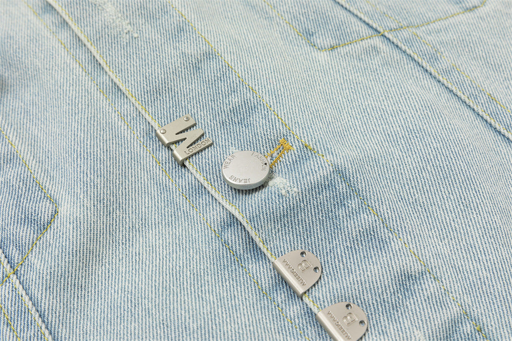 Detailed view of silver-tone buttons and metal tabs attached along the light wash denim front
