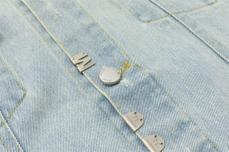 Detailed view of silver-tone buttons and metal tabs attached along the light wash denim front