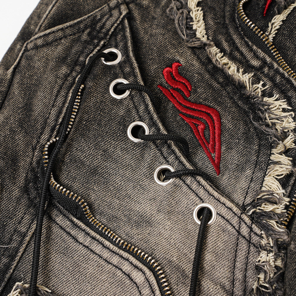 Close-up of front panel with zipper, metal eyelets, black laces, frayed denim, and red embroidery
