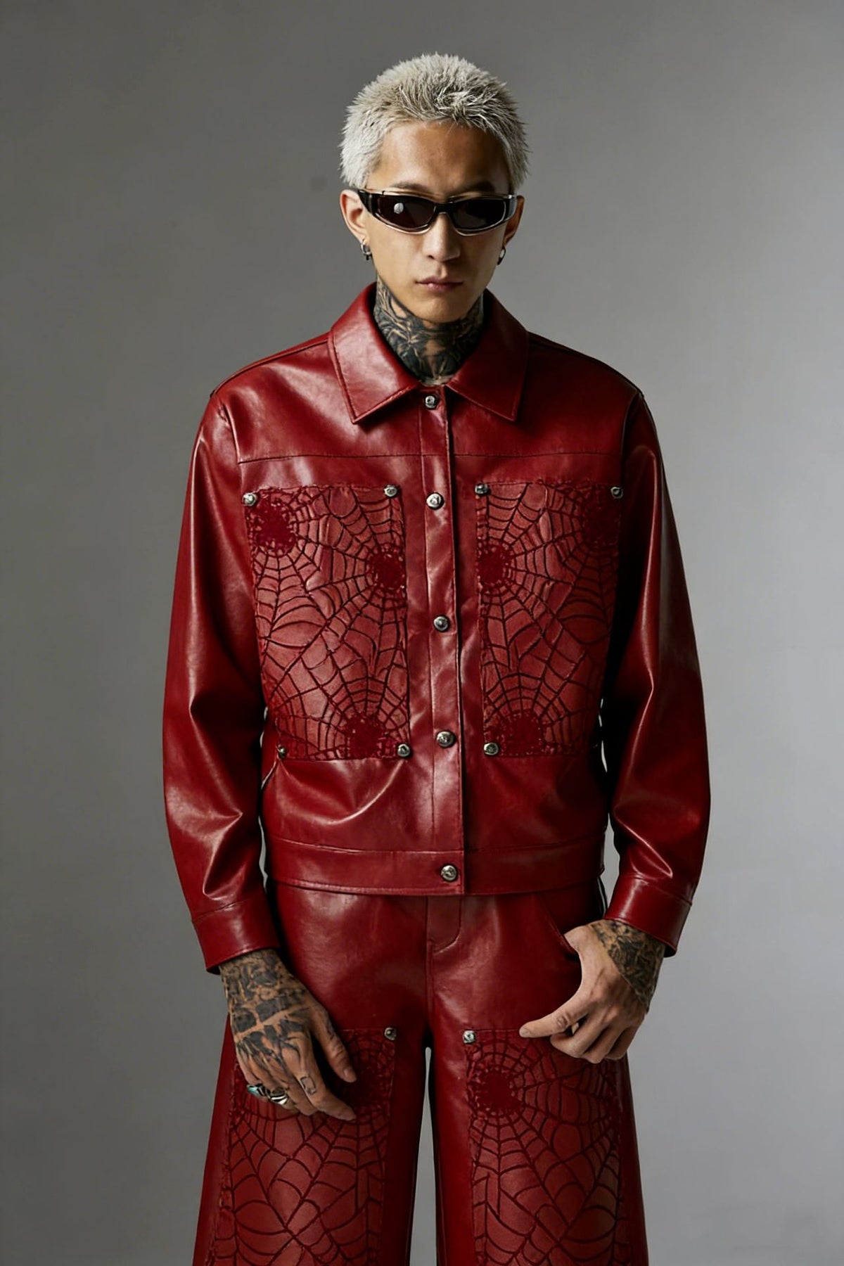 Oversized spiderweb embroidered PU leather jacket in crimson red with silver snap buttons, worn by male model