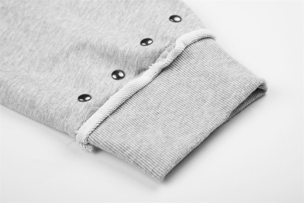Close-up of light gray hoodie sleeve cuff with ribbed trim and stud details