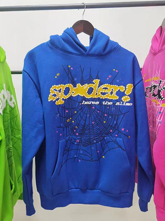 The Vivid Blue Sp5der Hoodie by Sp5der offers a bold streetwear look with its web print featuring &quot;spider!&quot; in bright yellow, surrounded by spiderwebs and vivid stars, nestled stylishly between green and pink hoodies.