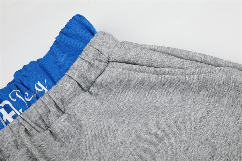 Close-up of gray sweatpants waistband and front rise with blue waistband visible