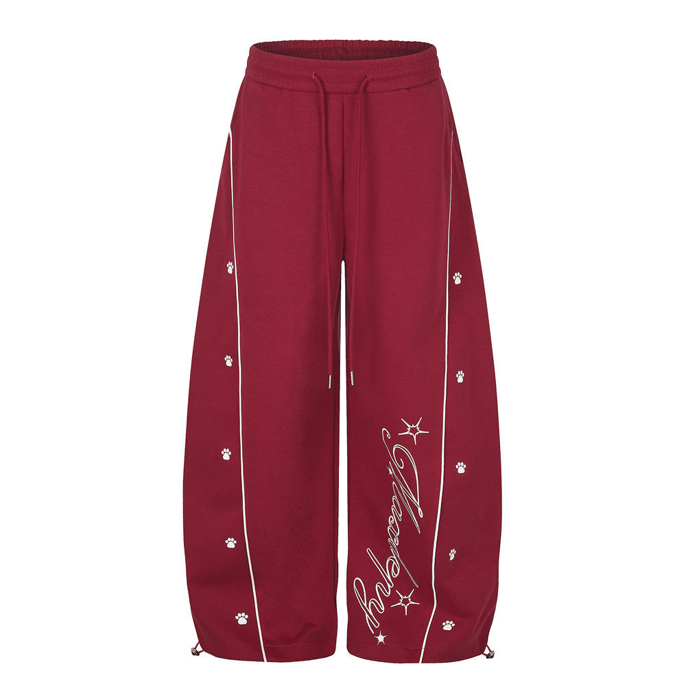 Pantalon de survêtement rouge à jambes larges, passepoil contrastant blanc incurvé, motifs empreinte de patte et étoile, lettrage manuscrit près de la h