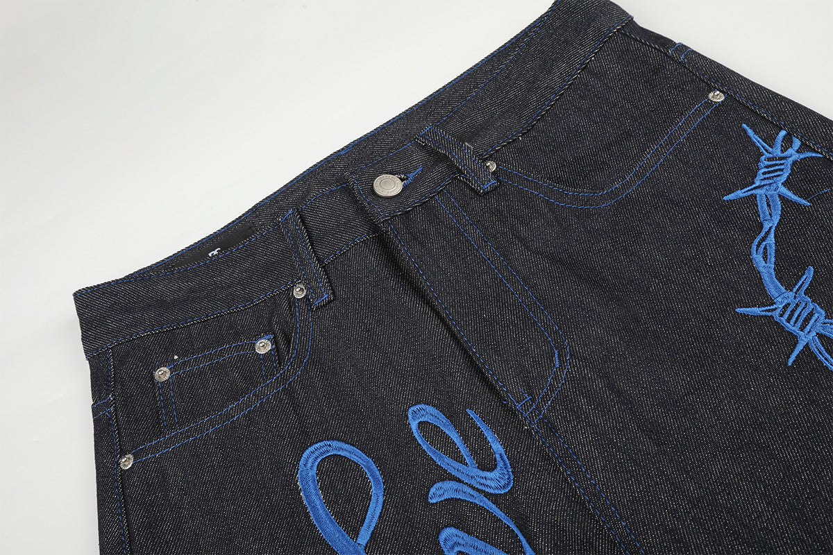 Jean baggy à jambes larges avec broderie bleue effet script et fil barbelé