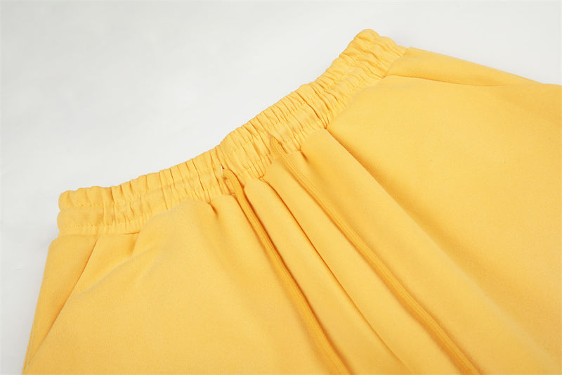 Close-up of yellow sweatpants waistband with elastic gathering and drawstring