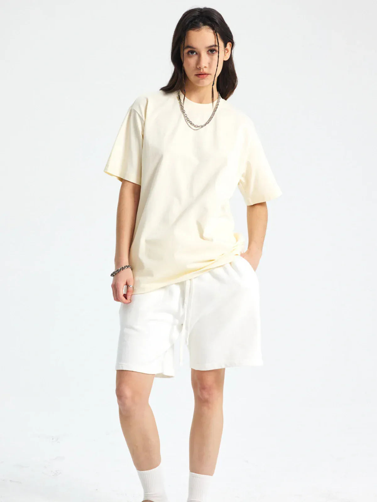 A person stands against a plain white background wearing the Custom Anime Character Cream T-Shirt - Personalized 230GSM 100% Cotton Tee, paired with white shorts, white socks, a chain necklace, and a bracelet.