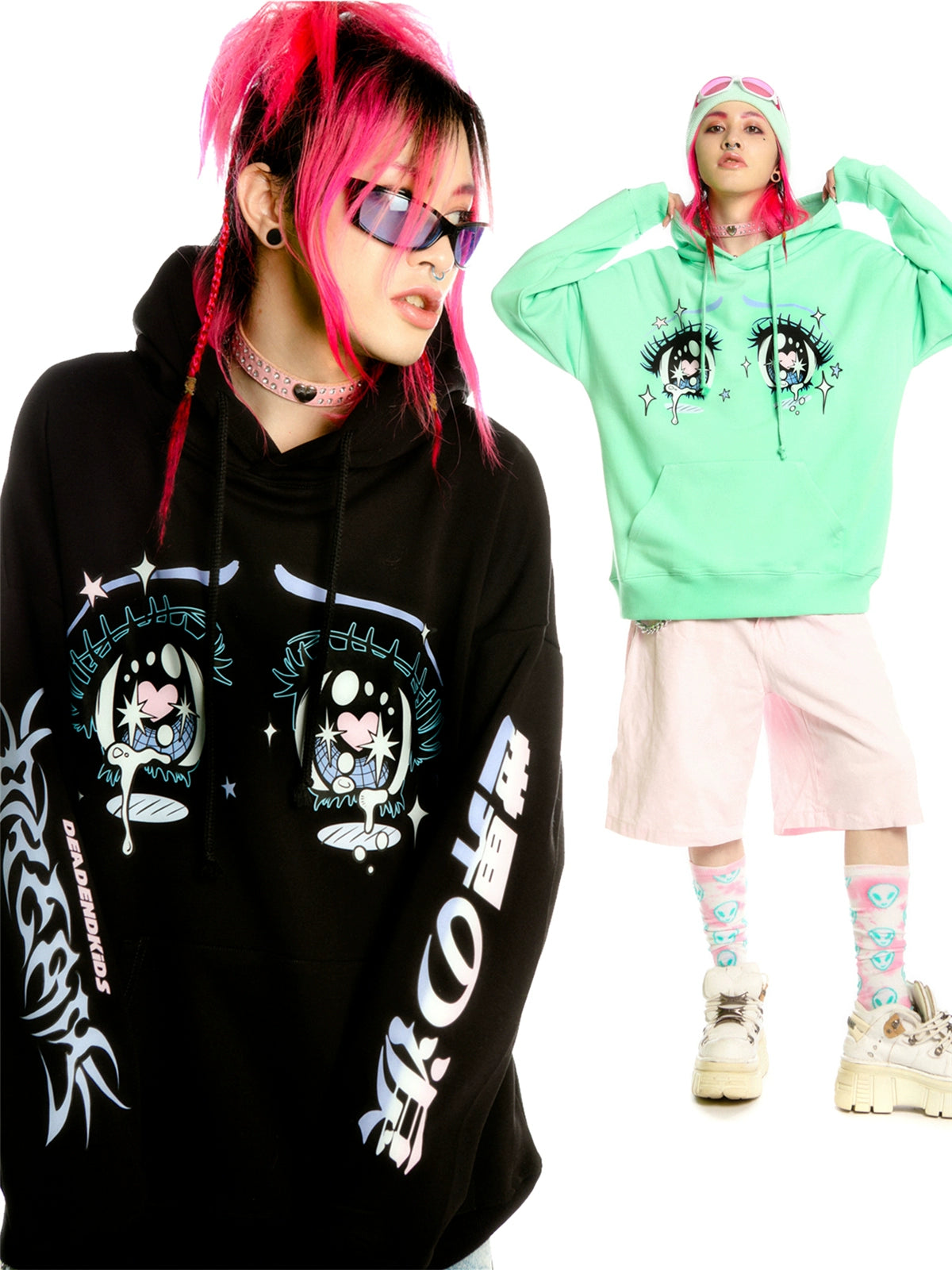 Two people flaunt anime-style streetwear: one in a Seakoff Kawaii Aesthetic Crying Eyes Hoodie and pink sunglasses, while the other wears a green hoodie with pink shorts, white boots, pink goggles, and blue socks featuring cartoon designs.