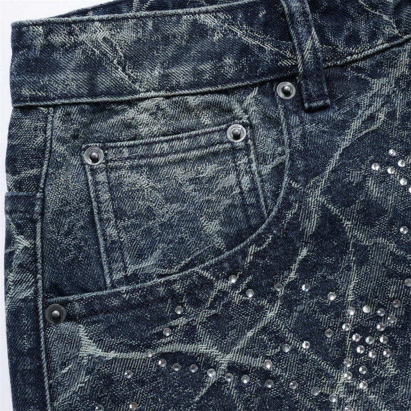 Close-up of front pocket and waistband on distressed jeans with rhinestone details