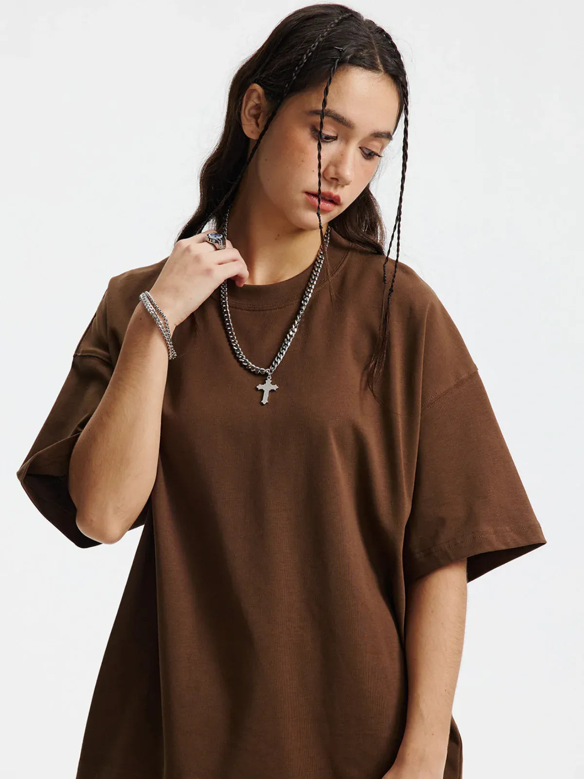 A woman with long dark hair and braids wears the Custom Anime Character Chocolate Brown T-Shirt—Personalized 230GSM 100% cotton tee—paired with layered chain necklaces, standing against a plain white background.