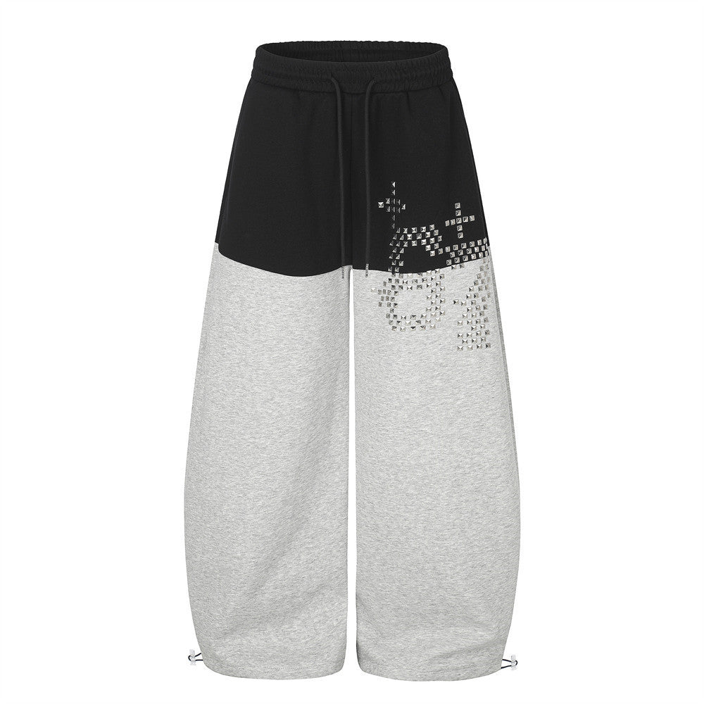 Pantalones de chándal de pierna ancha con bloques de color y gráfico de tachuelas piramidales plateadas, en paneles bicolor negros y grises