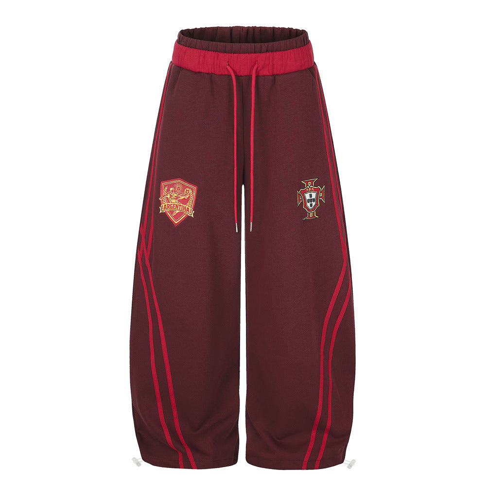 Men's wide-leg burgundy sweatpants with embroidered Argentina and Portugal shield badges and red contrast stripe piping