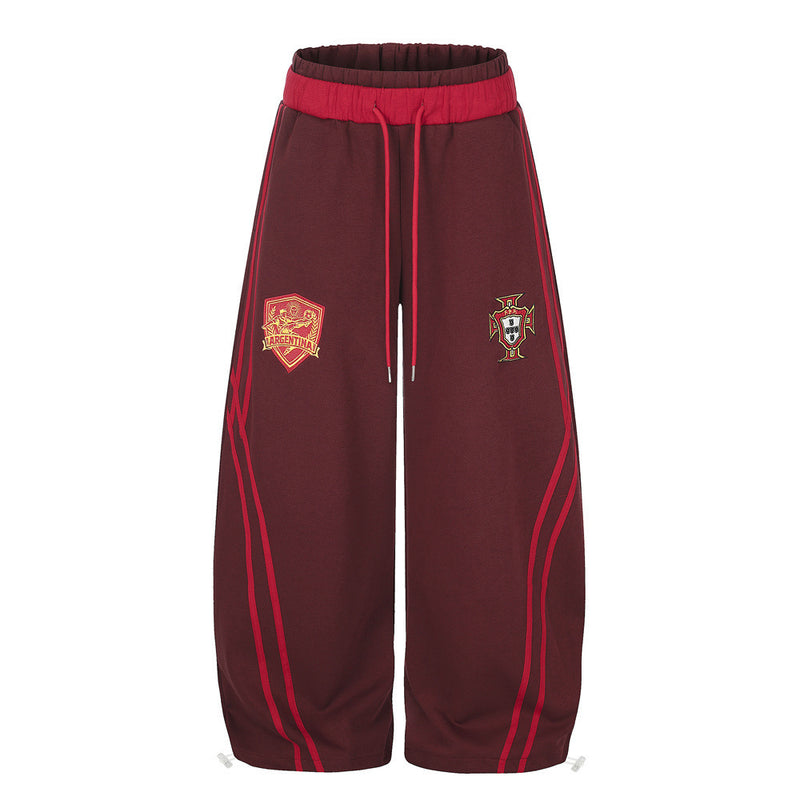 Men's wide-leg burgundy sweatpants with embroidered Argentina and Portugal shield badges and red contrast stripe piping