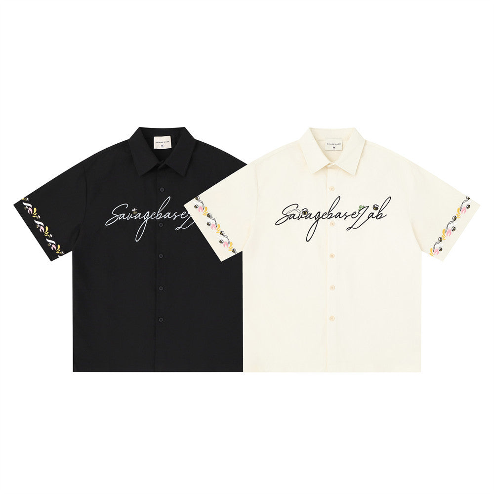 Black and cream short sleeve button-up shirts with floral embroidered sleeve trim and script logo on the chest