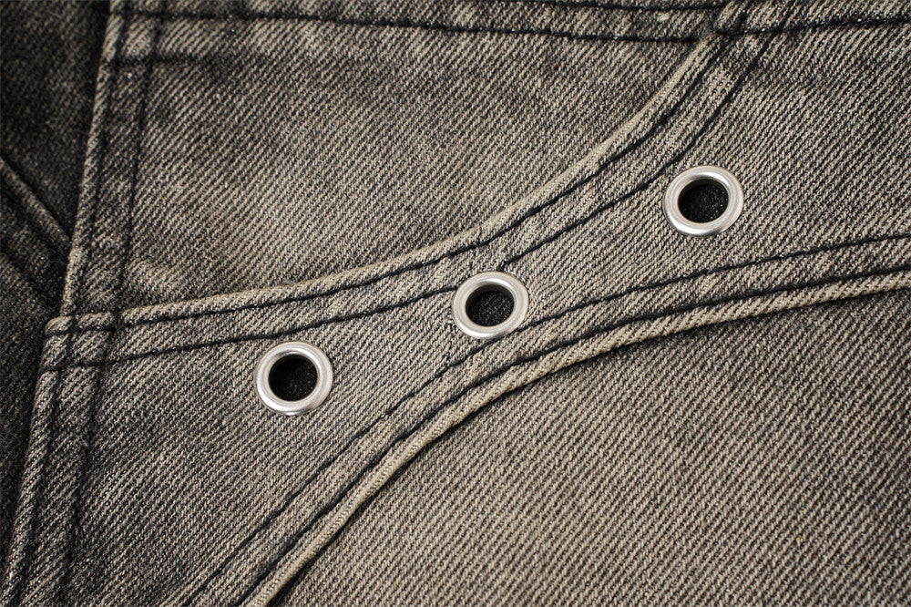 Close-up of faded patch pocket with three metal eyelets on black denim