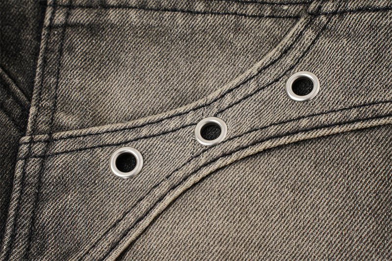 Close-up of faded patch pocket with three metal eyelets on black denim