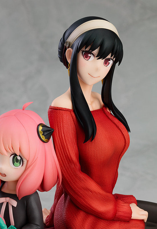 The Spy x Family Anya and Yor PVC Figure showcases a charming mother-daughter duo: one with long black hair in a red off-shoulder dress, and the other with short pink hair in a black outfit, set against a neutral gray background. This 15 cm figure captures their essence beautifully.