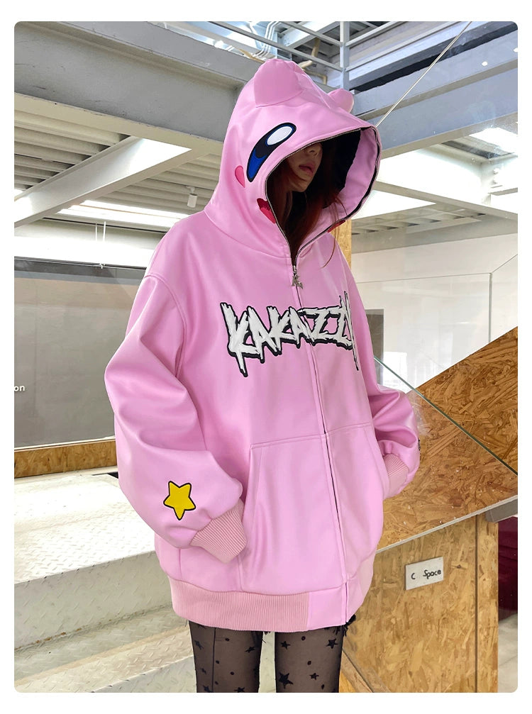 Wearing a Seakoff Kirby Pink Hoodie, an oversized anime zip-up sweatshirt with graffiti text and a cartoon-style face on the hood, someone stands against a staircase. The streetwear piece features a yellow star on the sleeve, paired with black star-patterned leggings.