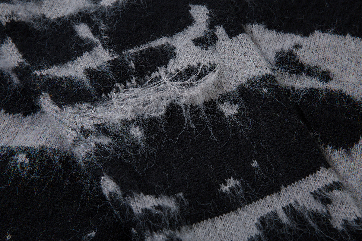 Close-up of distressed jacquard knit fabric showing loose gray fibers and irregular black patterning